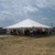 Celina Tent 40' x 40' Classic Series Pole Tent, Sectional Tent Top, Complete, outdoor event tent with a white canopy, set up on a grassy area under a partly cloudy sky, hosting a gathering with people and tables underneath.