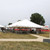 Celina Tent 40' x 60' Classic Series Pole Tent, Sectional Tent Top, Complete, large white event tent set up outdoors with supporting poles and red tables underneath.