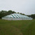 Celina Tent 80' x 100' Classic Series Pole Tent, Sectional Tent Top, Complete, pitched on a grassy field with a clear sky and trees in the background.