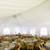 Celina Tent Frame Tent Liner 20' x 5' Mid, interior view of a large event tent with white fabric drapes and round tables set for celebration.