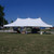 Celina Tent 20' x 40' Premiere I Series High Peak Pole Tent, 1 Piece Tent Top, Complete, outdoor event tent with high peaks and sturdy support poles set up on grassy area with blue sky in background.