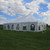 Celina Tent 30' x 45' Premiere II Series High Peak Pole Tent, Sectional Tent Top, Complete, outdoor event tent with a high peak design on a grassy field under a partly cloudy sky.