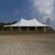 Celina Tent 40' x 60' Premiere II Series High Peak Pole Tent, Sectional Tent Top, Complete, white event tent set up outdoors on a dirt surface under a blue sky with clouds.