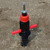 Screw In Flag Anchor, metal screw mechanism with red locking wings and black plastic body on sandy ground.