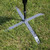 X-Stand Flag Anchor, metal stake with four extending arms securing a flagpole in grass.