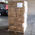 Bellbrook White Chair x120, stacked brown cardboard boxes containing the chairs on a pallet in a warehouse setting.