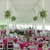 Center Pole Drape - 18' , elegant event tent with white drapes and floral decorations, set up for a formal banquet with pink tablecloths and white chairs.