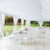 7' x 40' Leg Drape with Sash, elegant white fabric drapes creating a graceful outdoor event tent with tables and chairs underneath.