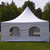 20' x 20' Pinnacle Series White Cross Cable Tent, complete with enclosed sides and clear window panels, set up outdoors on grassy ground with trees in the background.