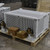 5 Ton Heating and Cooling Mobile Unit, industrial HVAC unit with metal casing and wheels for mobility placed on a wooden pallet in a warehouse setting.