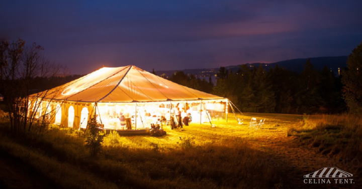 Large outdoor wedding tent setup with lighting and decor