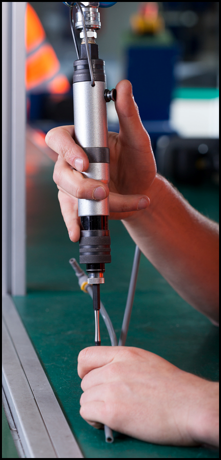 Hands using pneumatic screwdriver in a factory.