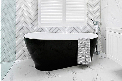 Luxurious black freestanding bath with a white interior, positioned against a window in a stylish bathroom setting