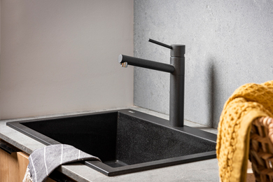 Black laundry tub and tap set-up accompanied by a baskets of fabric.