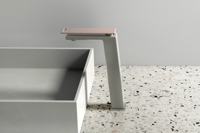 White sink and tap with pink lever on white granite tile