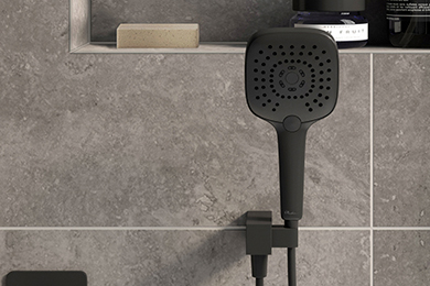 Close-up view of a shower head against a tiled grey wall