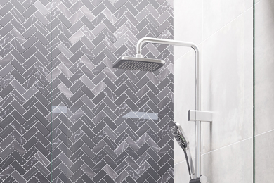 Close-up view of dual shower head against a tiled white wall
