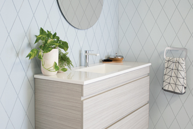 Wooden vanity with white countertop, green plant, diamond accent wall, and towel rail.