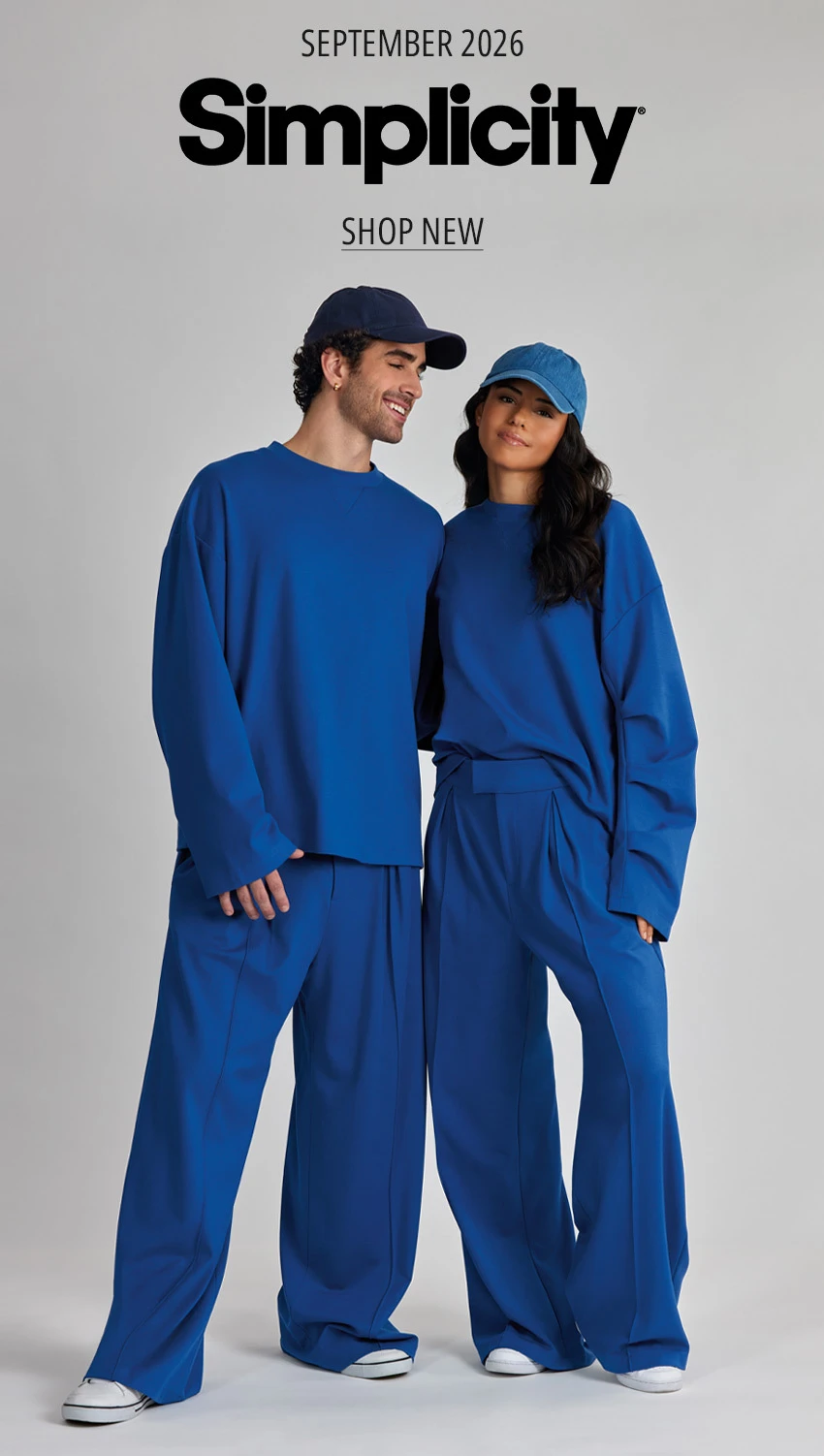 Simplicity September 2026 Couple wearing matching cobalt blue athleisure outfits on gray background.