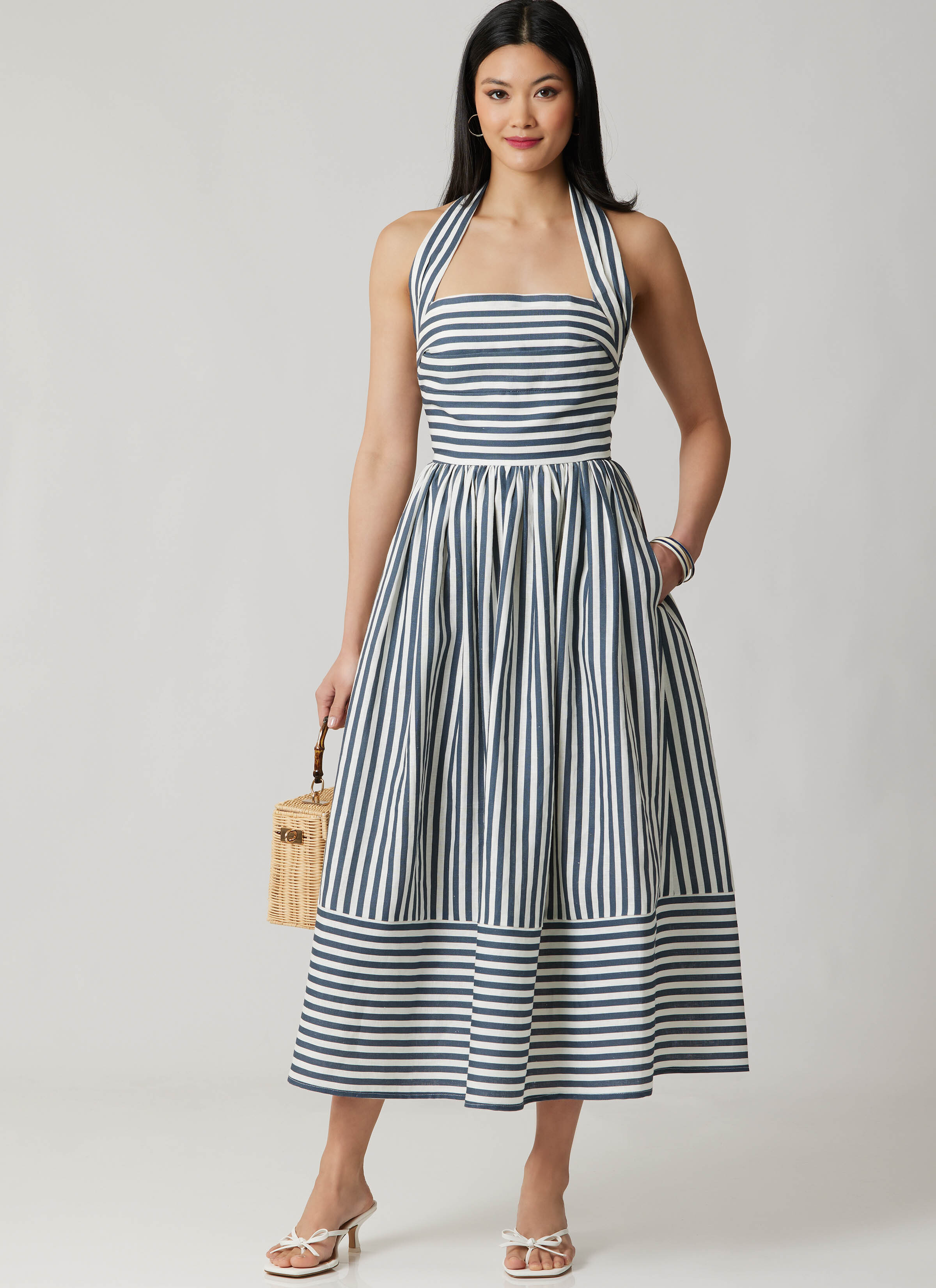 M8677 - Woman wearing striped halter neck dress with straw bag.