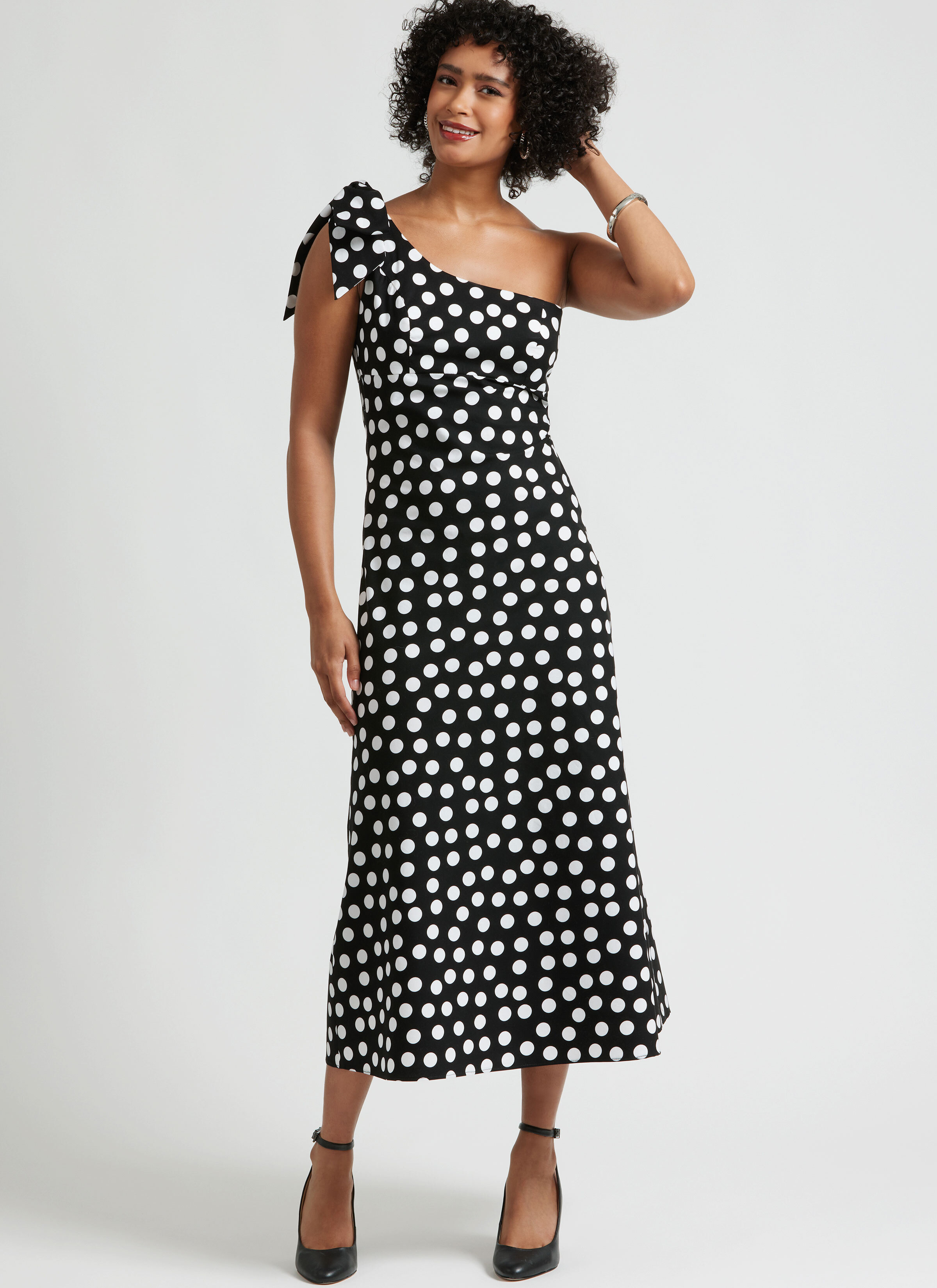 Woman wearing one shouldered white polka dot black dress