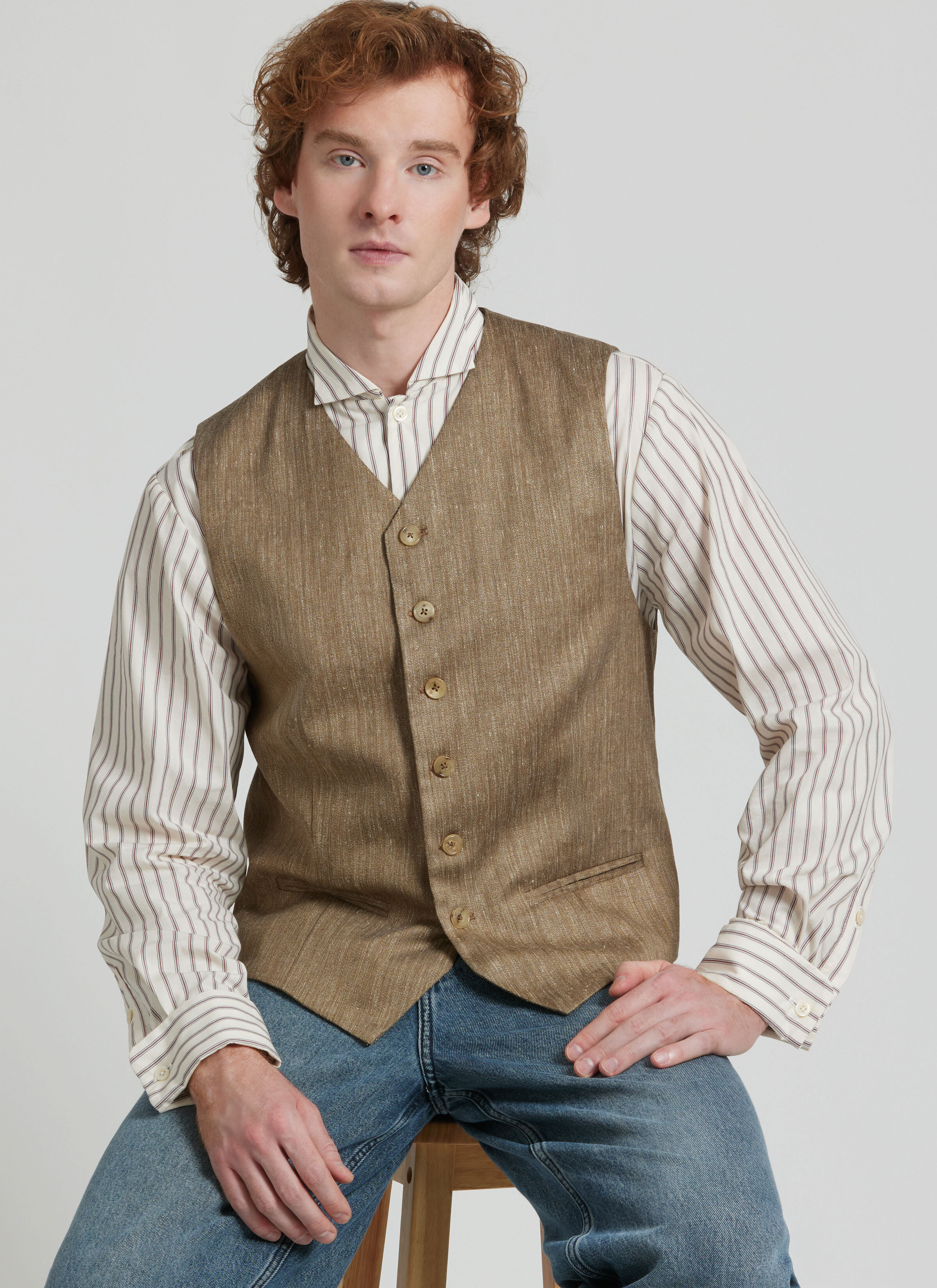 Man wearing brown vest with striped button up shirt