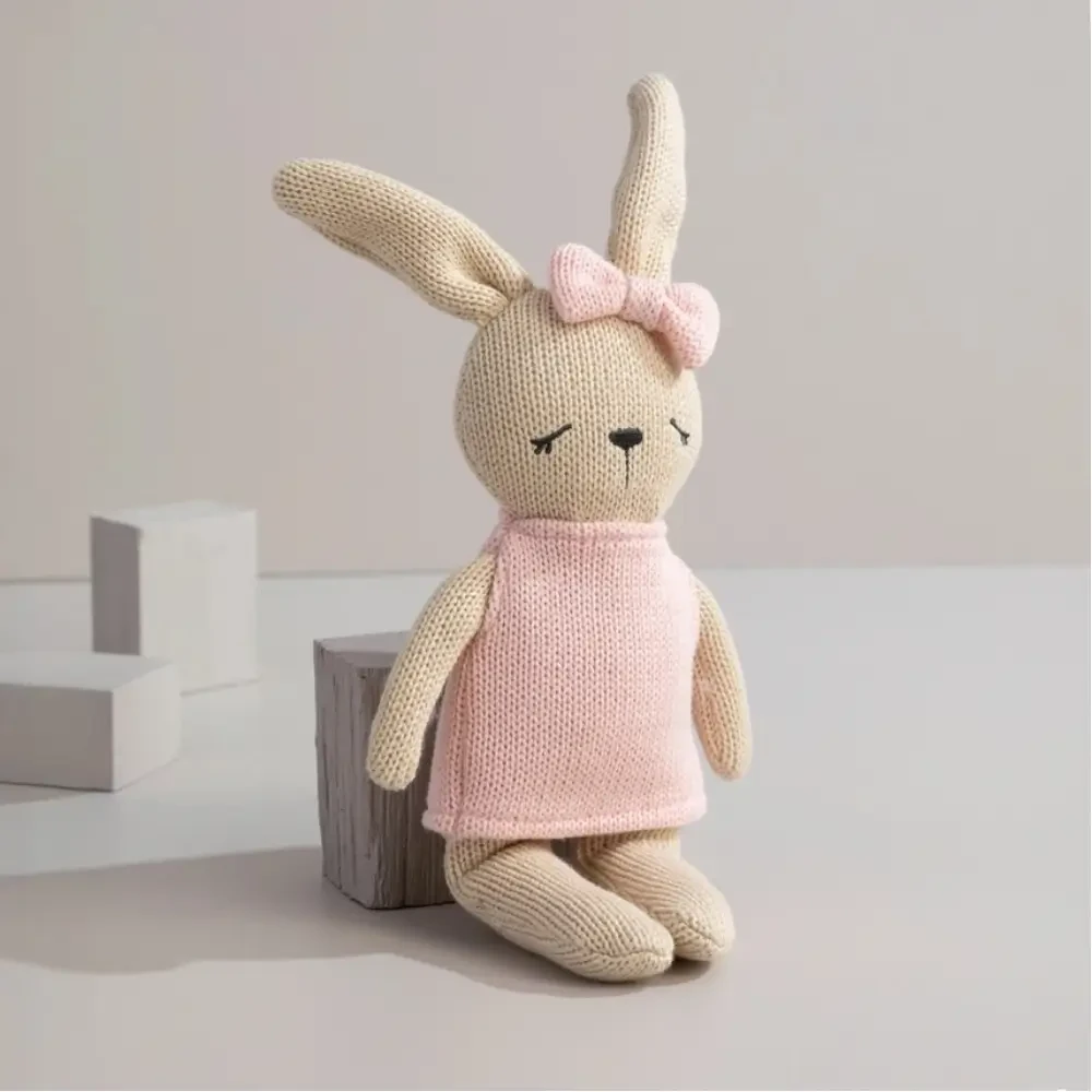 Meet Bella the Bunny, a soft 100% cotton knitted comfort toy with embroidered details, pink dress and bow. Perfect for cuddles, sensory play and gifting.