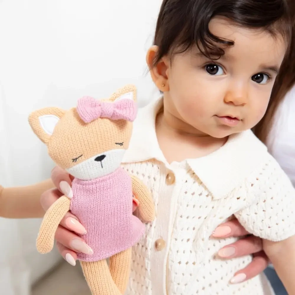 Meet Frankie the Fox, a soft 100% cotton knitted toy with a pink dress, matching bow and embroidered details. Perfect for cuddles, comfort and sensory play.