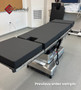 Refurbished Amsco 3085 SP Surgical Table in clinical setting, featuring black cushions, stainless steel base in a medical room.