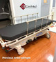 Refurbished Hill-Rom P8005 in a clinic room with a black mattress.