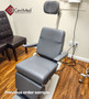 Reliance 7000 ENT exam chair with gray upholstery and articulating headrest, in a medical room with dark leather guest chairs and visible power cables.