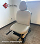 Light gray Midmark 630 exam chair with stirrups in carpeted exam room near window.