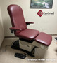 Wine Midmark 647 with adjustable arms and footrest, placed in a medical exam room.