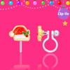 Girl Nation Santa hat clip-on earring showing glittery red enamel, green holly leaves, sparkling red jewel accent and transparent silicone clip on festive pink background