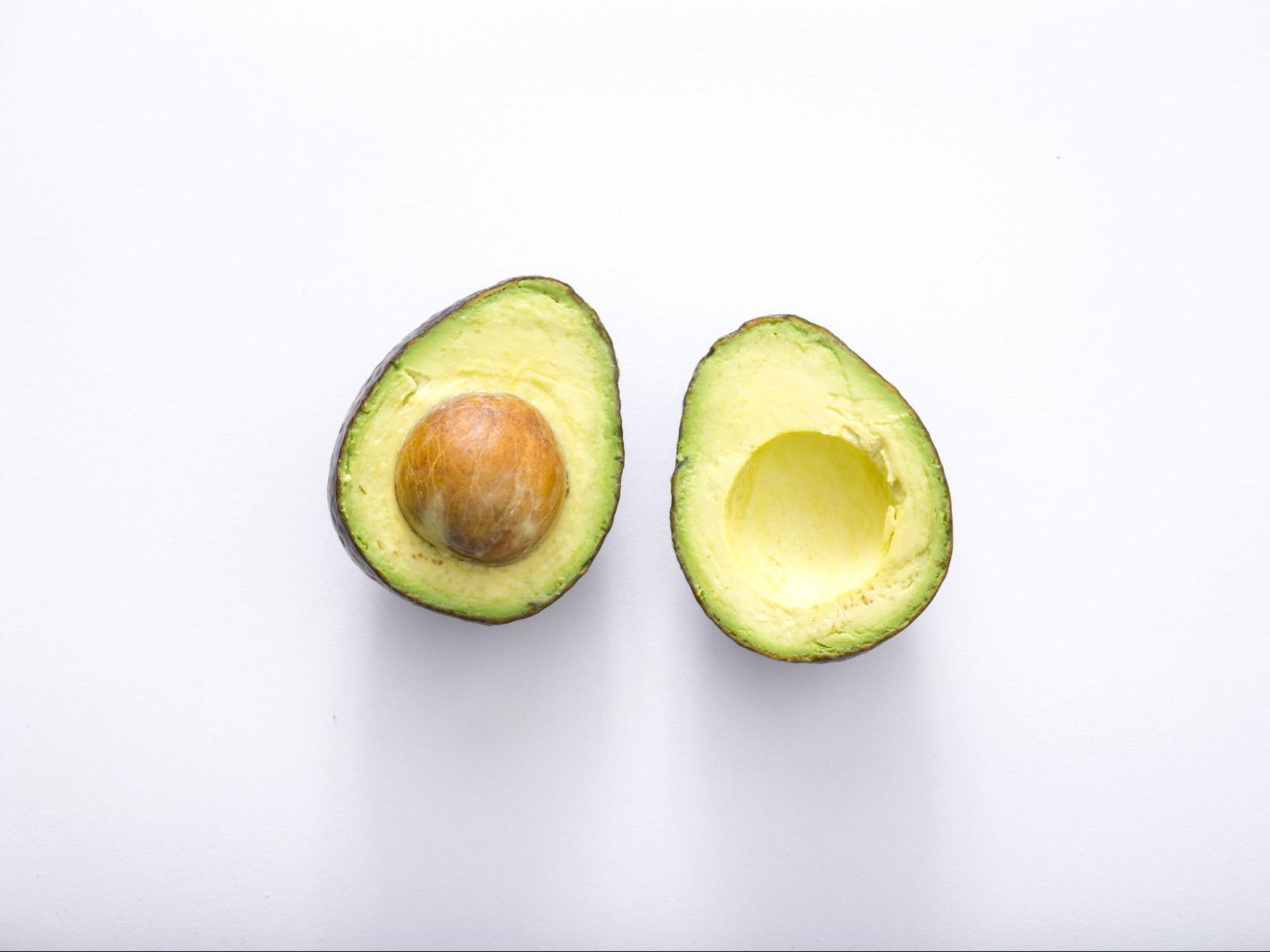 An avocado sliced in half on white surface
