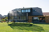 Akrobat Challenger Plus 17x10 trampoline in a garden setting by house