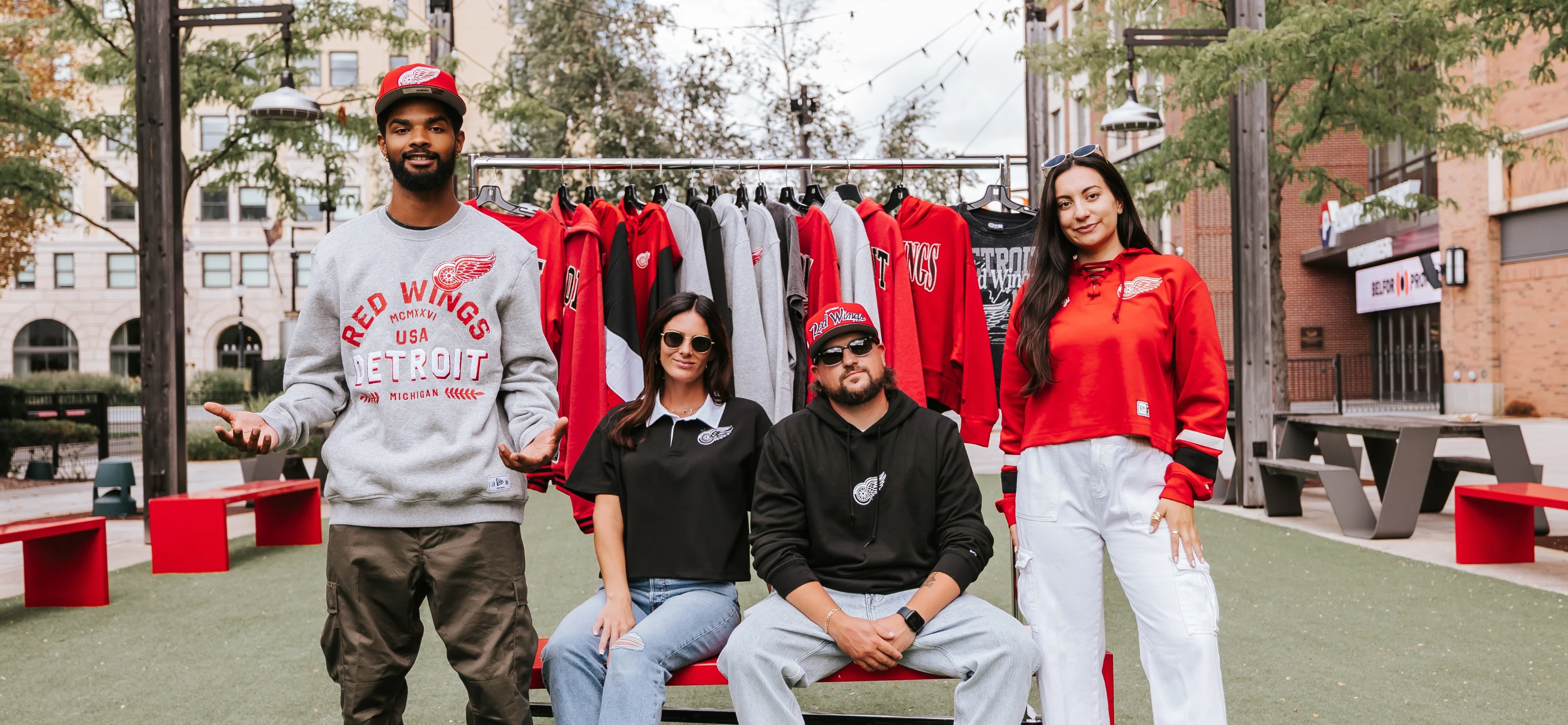 two males and two females modeling the new New Era apparel  in front of a rack of additional New Era apparel data-size=