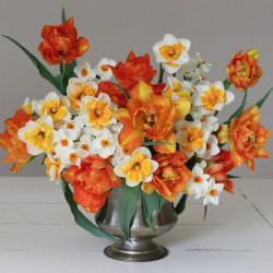 A lush springtime flower arrangement that combines orange tulips with orange and white daffodils.