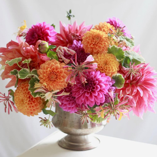 A flamboyant tabletop arrangement of pink and orange dahlias, featuring the timeless varieties Maarn, Cantiflora and Penhill Dark Monarch