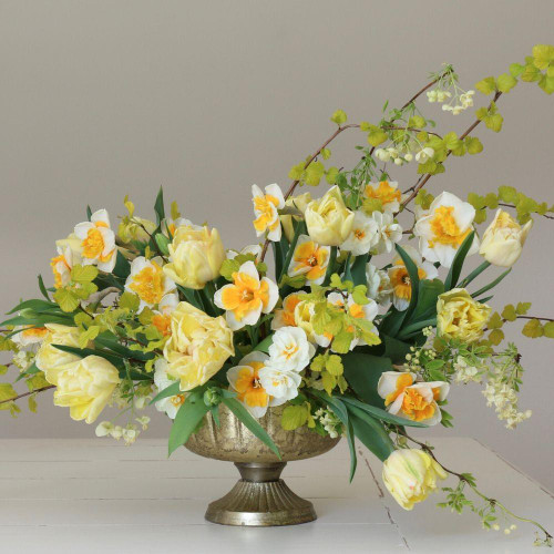 An exuberant arrangement of spring flowers, featuring double white daffodils, white and orange daffodils and yellow double tulips.