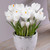 The white flowers of crocus Jeanne d'Arc blooming in a small white ceramic pot.