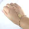 Filipino-inspired Black Dasal Hand Rosary Bracelet worn on a hand facing upward, featuring a gold-plated stainless steel rosary chain with finger loop and adjustable wrist sizing.