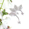 Silver Reyna Ear Cuff displayed on a clean white background with delicate white decorative flowers beside it, highlighting its bold statement silhouette inspired by the Philippine three stars and sun. This elegant right-ear cuff blends regal Filipina-inspired design with a soft, elevated presentation perfect for showcasing its dramatic details.