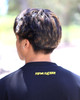 Close-up of a young man wearing the Kapwa Legacy Tee, highlighting the raised 3D puff "Kapwa Kultura" logo on the back collar. Premium Filipino streetwear T-shirt made from 100% ring-spun cotton with 240 GSM heavyweight pre-shrunk fabric and high-quality branded detailing.