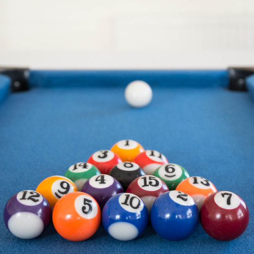 A Mini Table Top Pool table with blue felt. The colourful balls are racked in a triangle with the white cue ball ready to break.