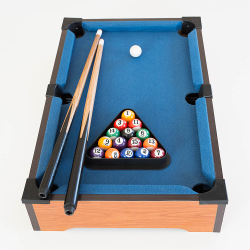The Mini Table Top Pool set with blue felt, balls racked in a triangle, and two cues resting on the side, ready for a game.