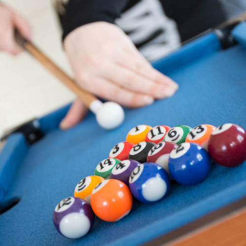Close-up of the Mini Table Top Pool game, showing colourful balls racked on the blue felt as a player aims to break.
