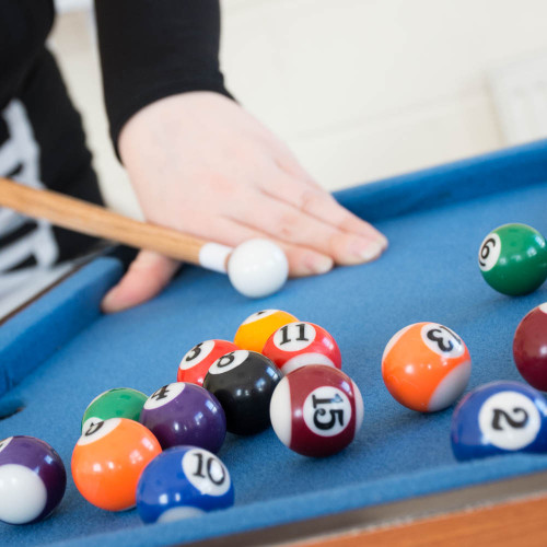 A person lines up a shot with a cue ball on the #winning Mini Table Top Pool table, with colourful balls clustered nearby.