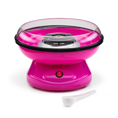 A bright pink candy floss maker with a clear splatter guard and red power switch. A white measuring scoop rests nearby.
