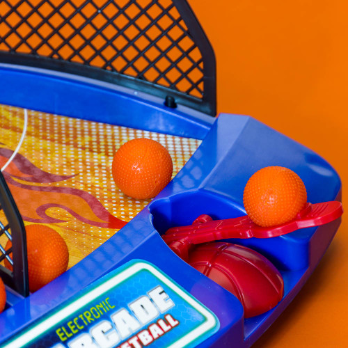 A detailed close-up of the blue Electronic Arcade Basketball game showing the red launcher, orange balls, and flame-graphic court.